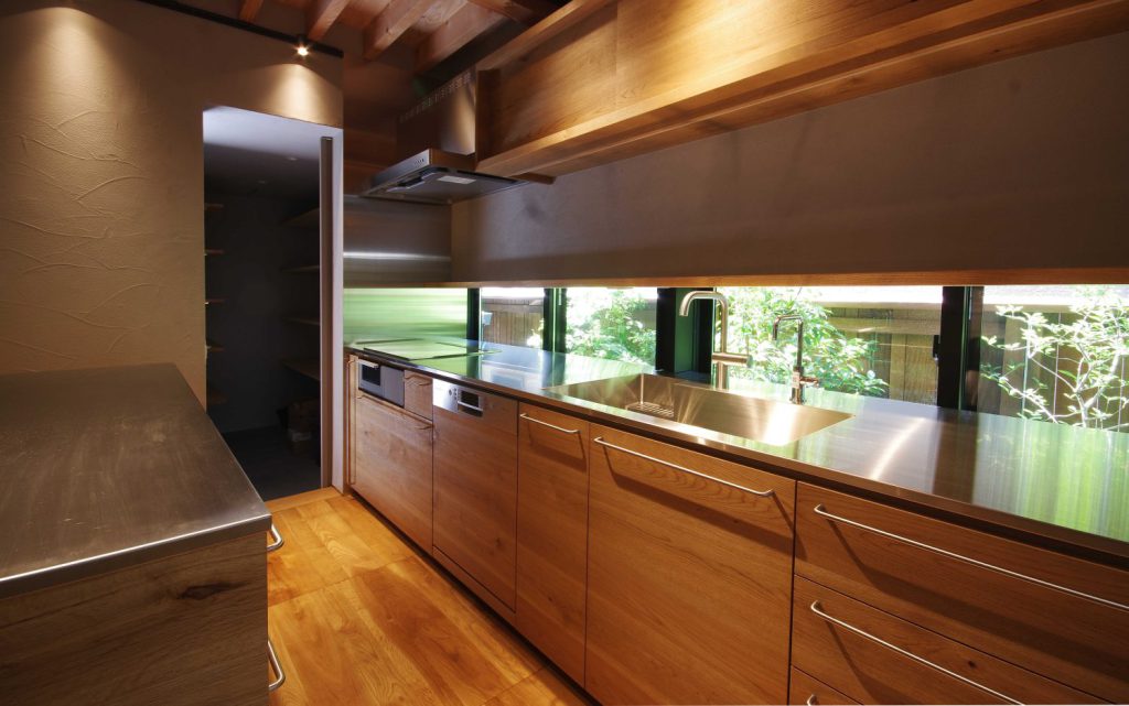 ワークトップにステンレスを採用したキッチン。ドアパネルは天然の木材。