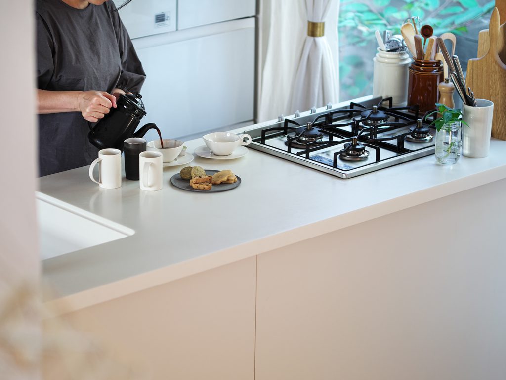 ワークトップにセラミックタオルを採用したキッチン。真っ白なセラミックタイルのワークトップは、同じ白でもどこか透け感があって柔らかな奥行きを感じる。