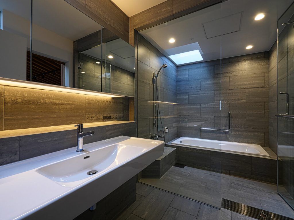 KOBE STYLEが手がけたオーダーバスルーム。浴室や洗面スペースの壁と床にRevigresのグレー系のタイルが使用されている。